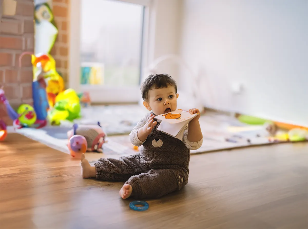 tout-petit explorant un livre dans l’espace d’éveil de la crèche